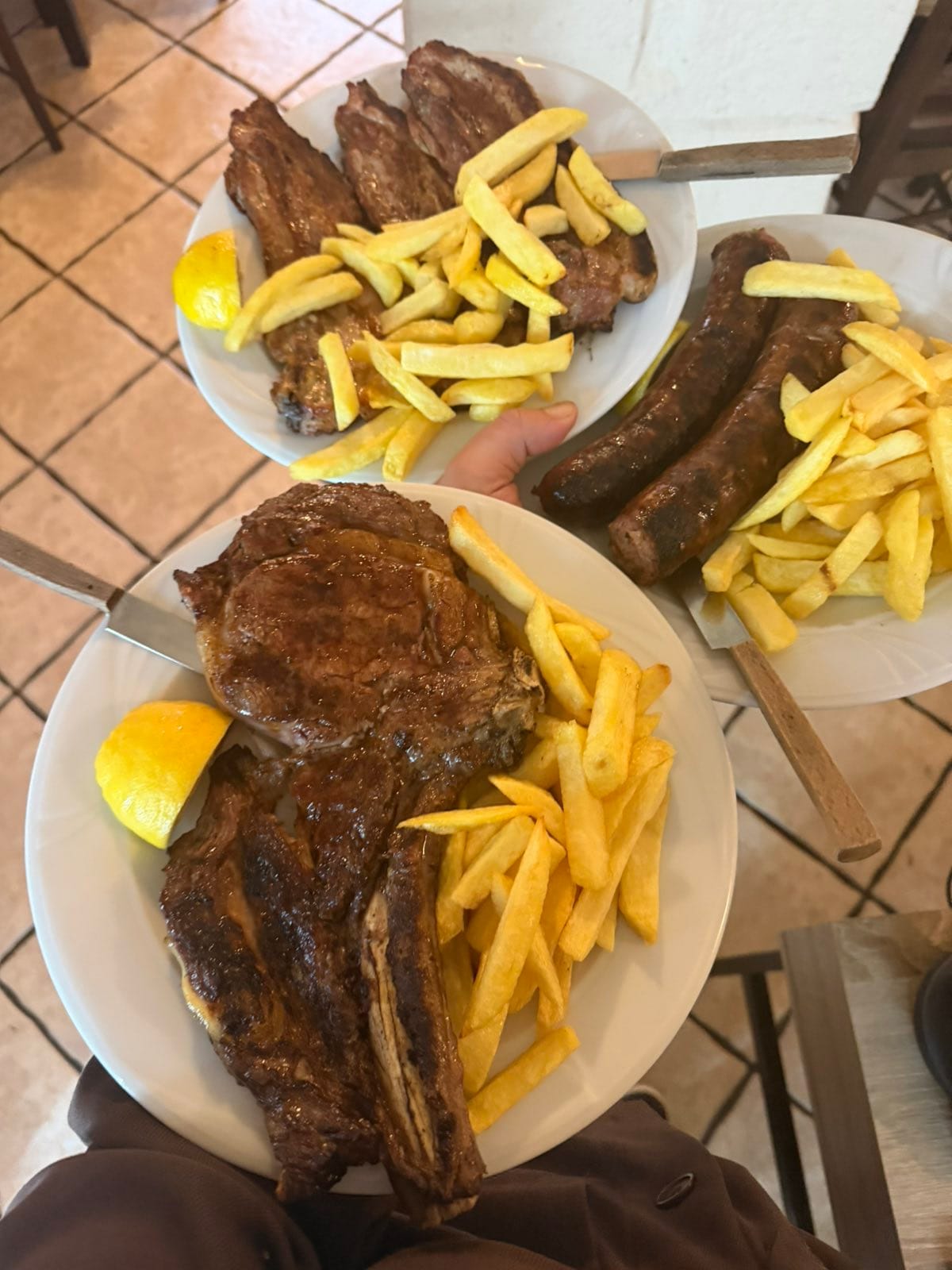 Mixed grill platter with veal chop, lamb ribs, and sausages with golden fries
