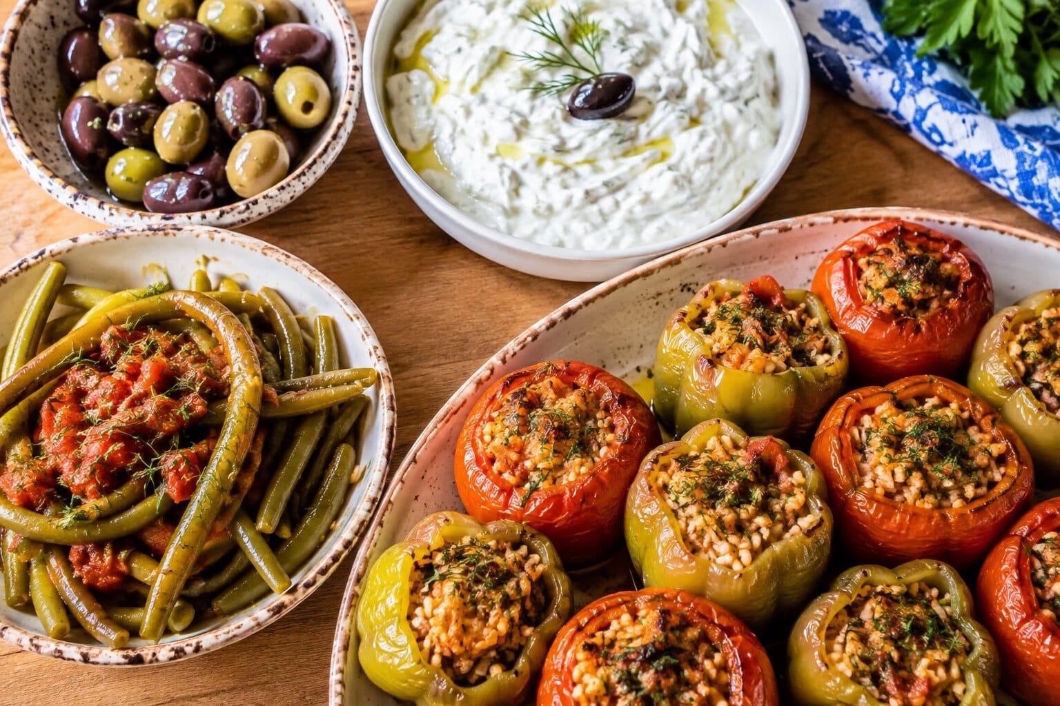 Traditional Greek cooked dishes - stuffed tomatoes and peppers (gemista), green beans in tomato sauce, tzatziki and olives