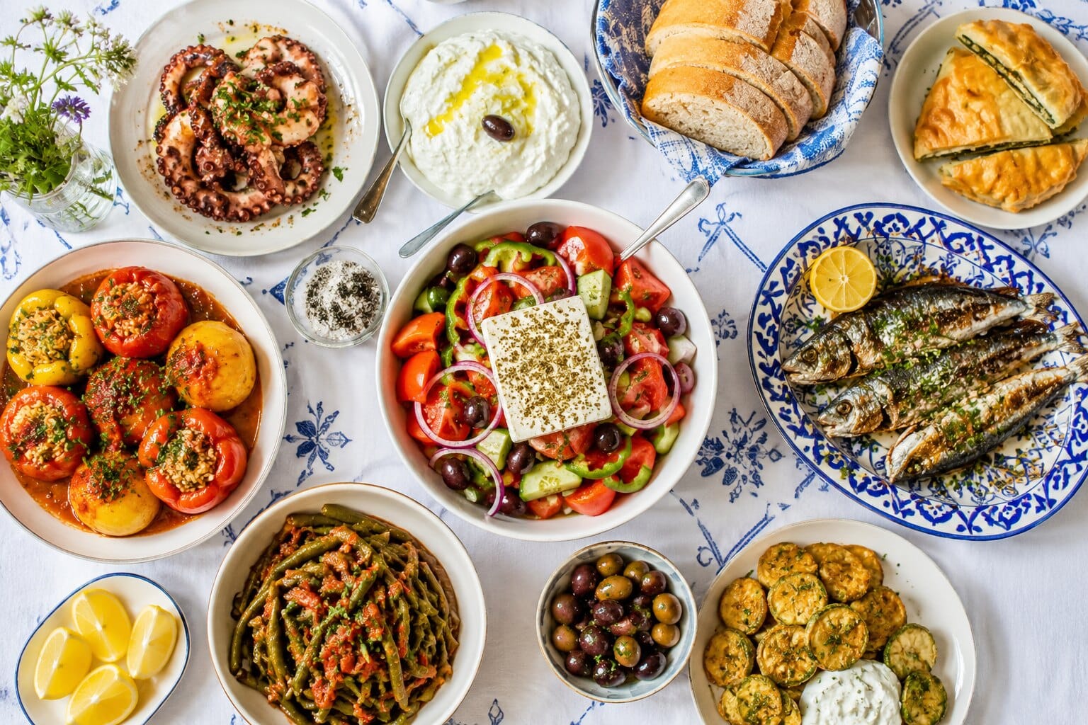 Greek meze table spread with grilled octopus, tzatziki, spanakopita, sardines, Greek salad, gemista and courgette fritters